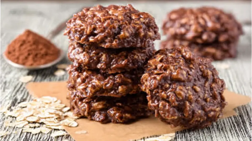 Stack of fudgy no bake chocolate oatmeal cookies with oats on parchment paper